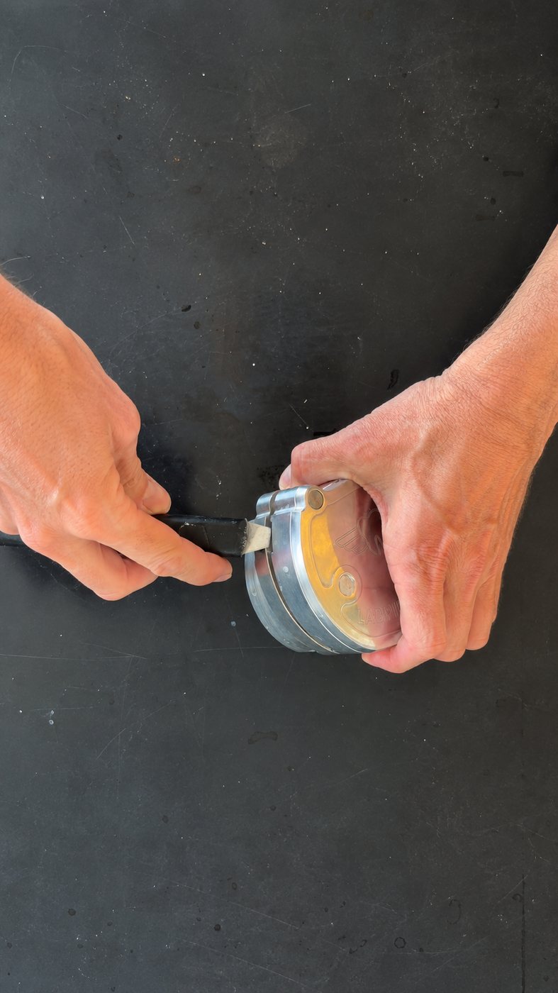 Hands using a deflasking tool to separate the flask sections at the seam
